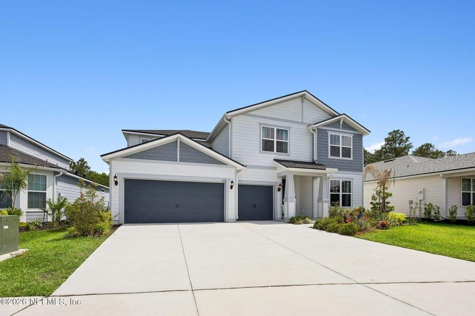 A two-story house with light blue siding, a three-car garage, and a concrete driveway — 978 ROOSTER HOLLOW WAY, MIDDLEBURG, FL