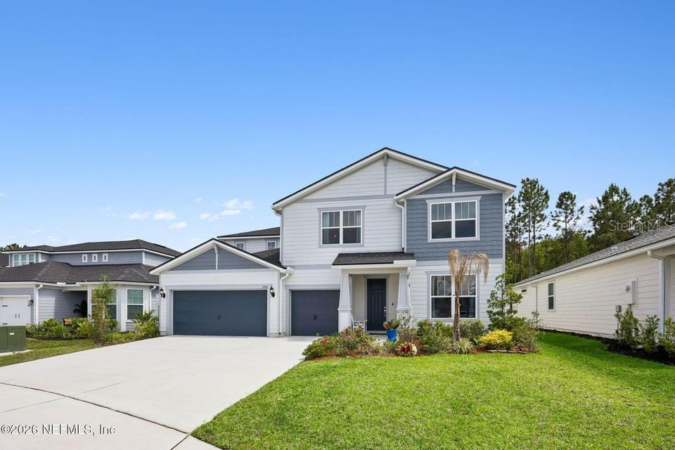 A two-story house with a blue and white exterior, a three-car garage, and a lawn — 978 ROOSTER HOLLOW WAY, MIDDLEBURG, FL