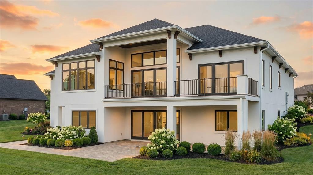 A modern two-story white house with black-framed windows, a balcony, and a paved patio — 161 TRANQUIL MIRROR LAKE COURT Lot 9, CLERMONT, FL
