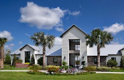 A modern community building with a metal roof, stone accents, and two palm trees — 10732 OAK BEND DRIVE, PARRISH, FL