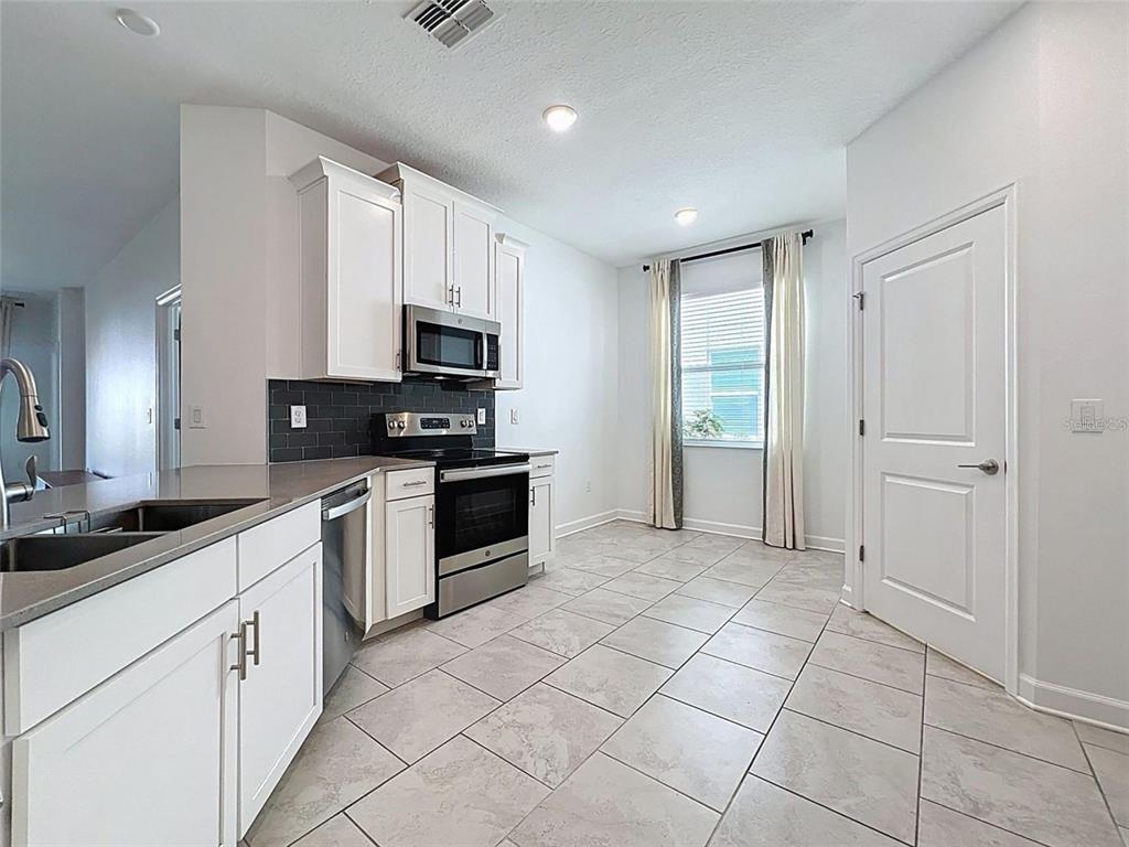 A living and dining area features tile flooring, a leather sectional, and wall-mounted wooden shelving — 195 PRESTON AVE, DAVENPORT, FL