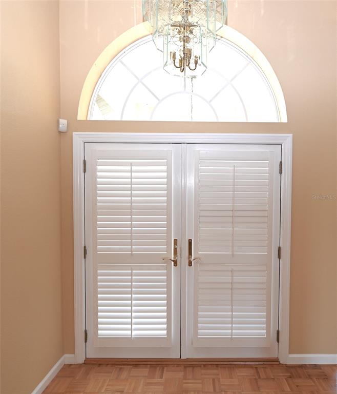 A set of white double doors with shutters sits below an arched window and chandelier — 6535 CANARY STREET, SARASOTA, FL