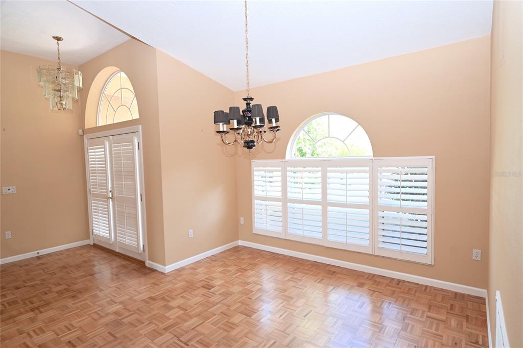 A dining room with parquet wood floors, a chandelier, and arched windows with shutters — 6535 CANARY STREET, SARASOTA, FL