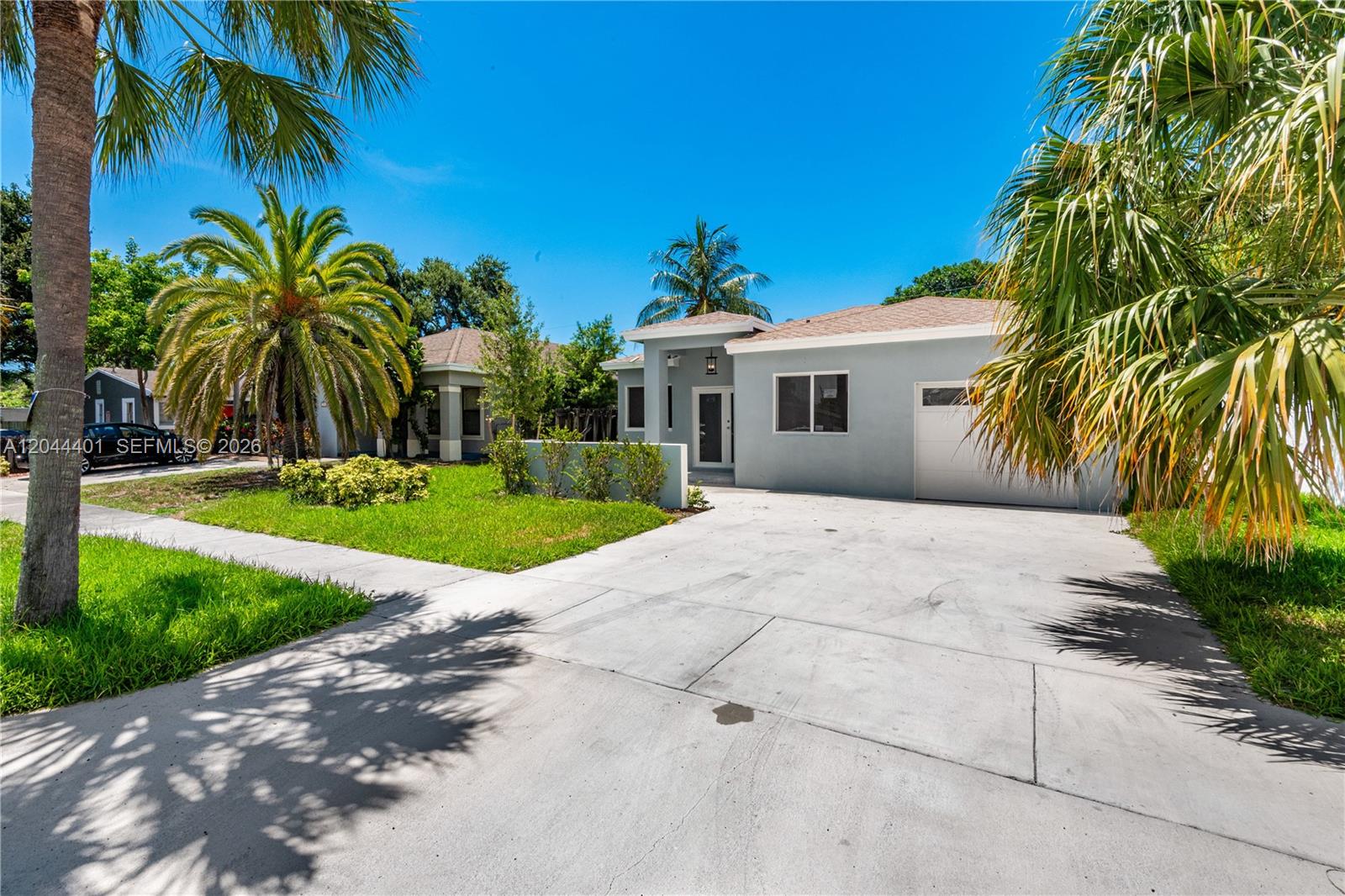 A light gray single-story house features a concrete driveway, a small lawn, and palm trees — 731 SW 6th St, Dania Beach FL 33004, DANIA BEACH, FL