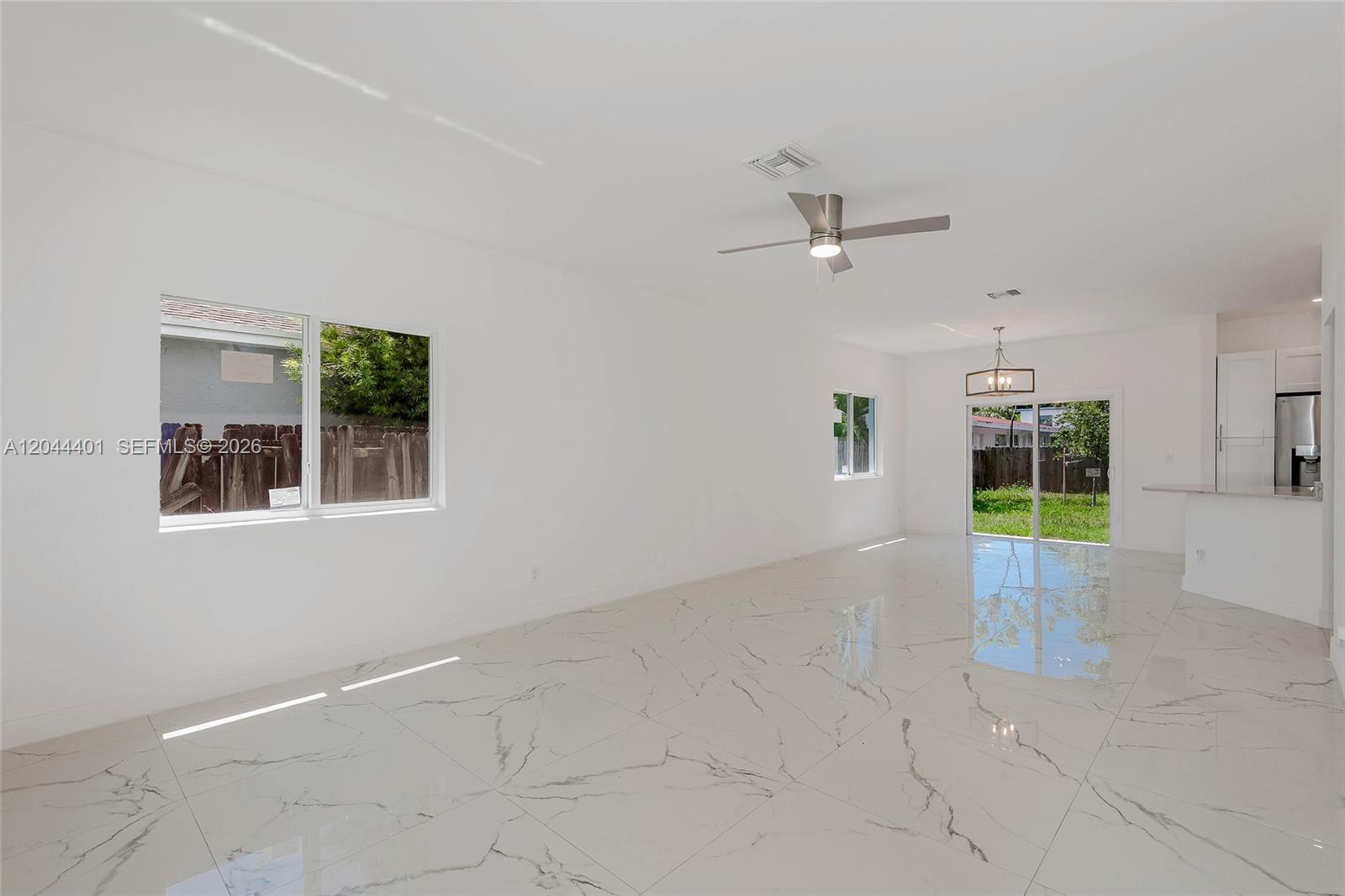 A bright, open-concept living area features white marble-look tile flooring and a ceiling fan — 731 SW 6th St, Dania Beach FL 33004, DANIA BEACH, FL