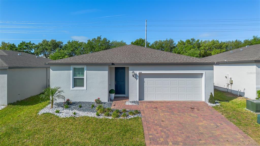 A single-story house with a gray stucco exterior, dark blue front door, and paver driveway — 3096 CASSIDY LANE, HAINES CITY, FL
