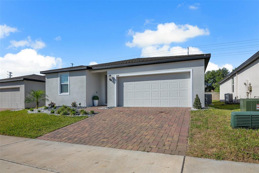 A single-story house with a gray stucco exterior, a brick paver driveway, and a garage — 3096 CASSIDY LANE, HAINES CITY, FL