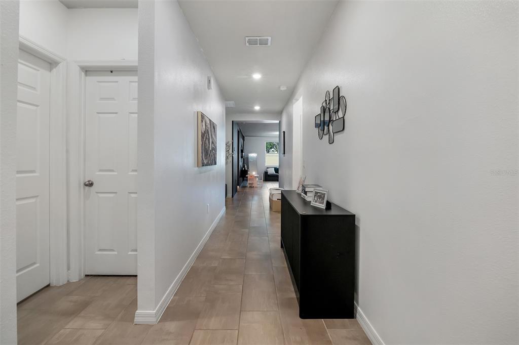 A long hallway features light tile flooring, white walls, and a black console table — 3096 CASSIDY LANE, HAINES CITY, FL