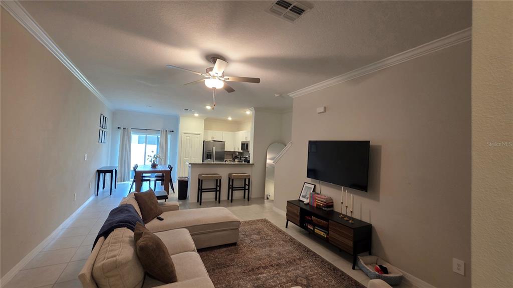 A living room with a sectional sofa, television, and an open kitchen with bar seating — 36352 WELL HILL WAY, ZEPHYRHILLS, FL