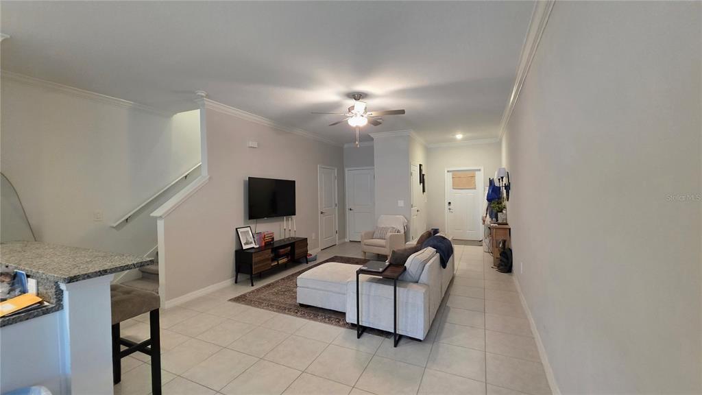 A living room features tile flooring, a sectional sofa, a television, and a staircase — 36352 WELL HILL WAY, ZEPHYRHILLS, FL