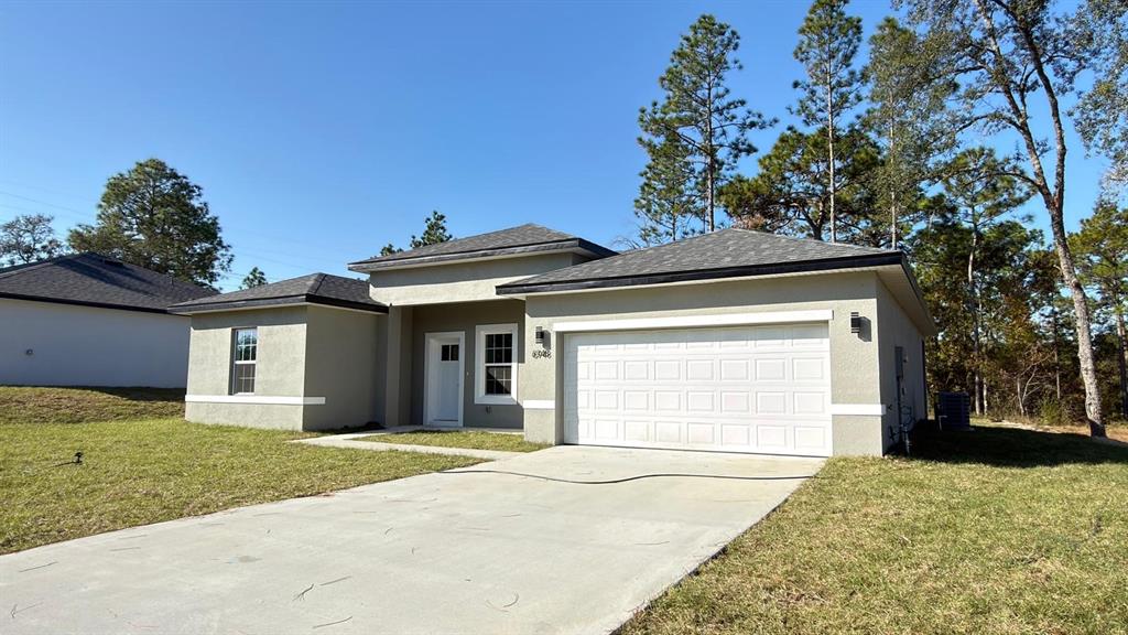A single-story house with a beige stucco exterior, a two-car garage, and a concrete driveway — 6948 N ELKCAM BOULEVARD, CITRUS SPRINGS, FL