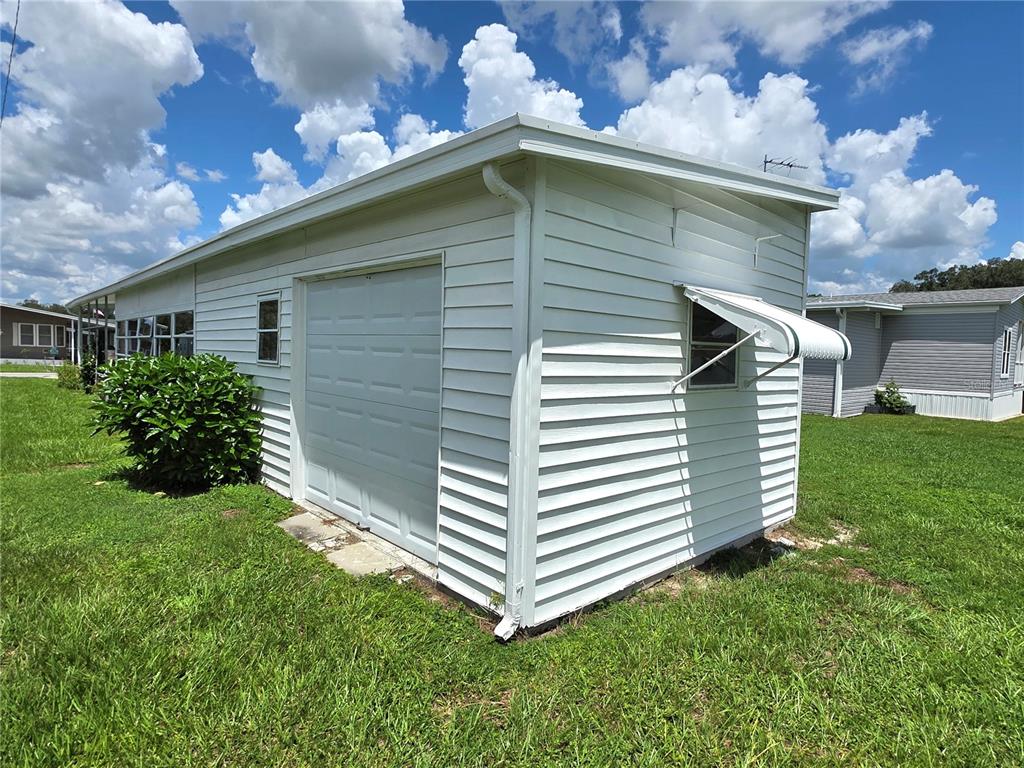 A white detached garage with horizontal siding and a small window with an awning — 5452 JOYCE STREET, ZEPHYRHILLS, FL