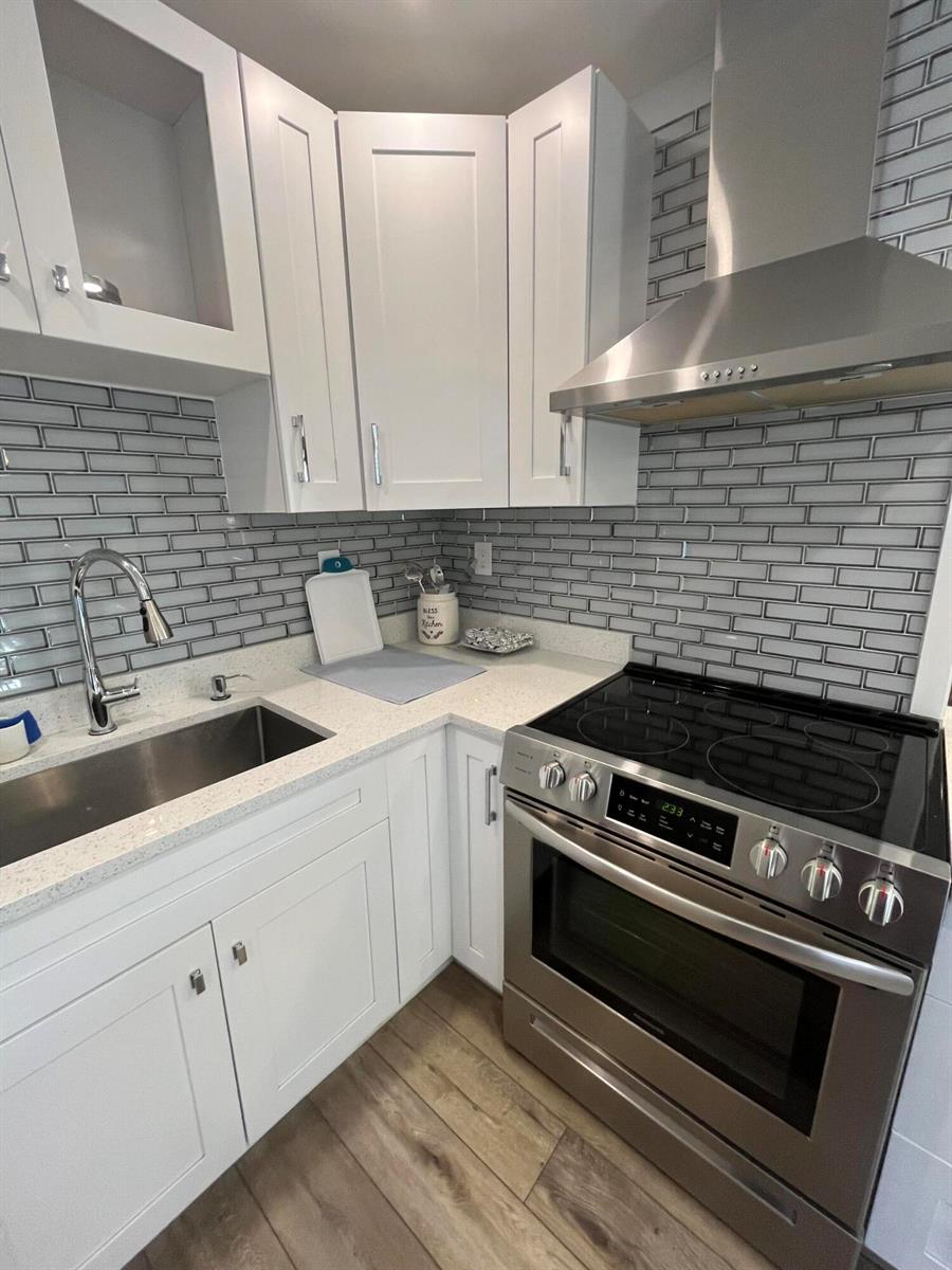 A kitchen features white cabinets, stainless steel appliances, and gray subway tile backsplash — 812 Burgundy Q, Delray Beach FL 33484, DELRAY BEACH, FL