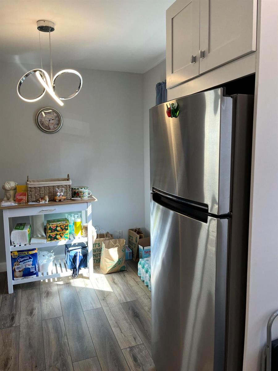 A kitchen area features a stainless steel refrigerator, a white utility cart, and a modern light — 812 Burgundy Q, Delray Beach FL 33484, DELRAY BEACH, FL