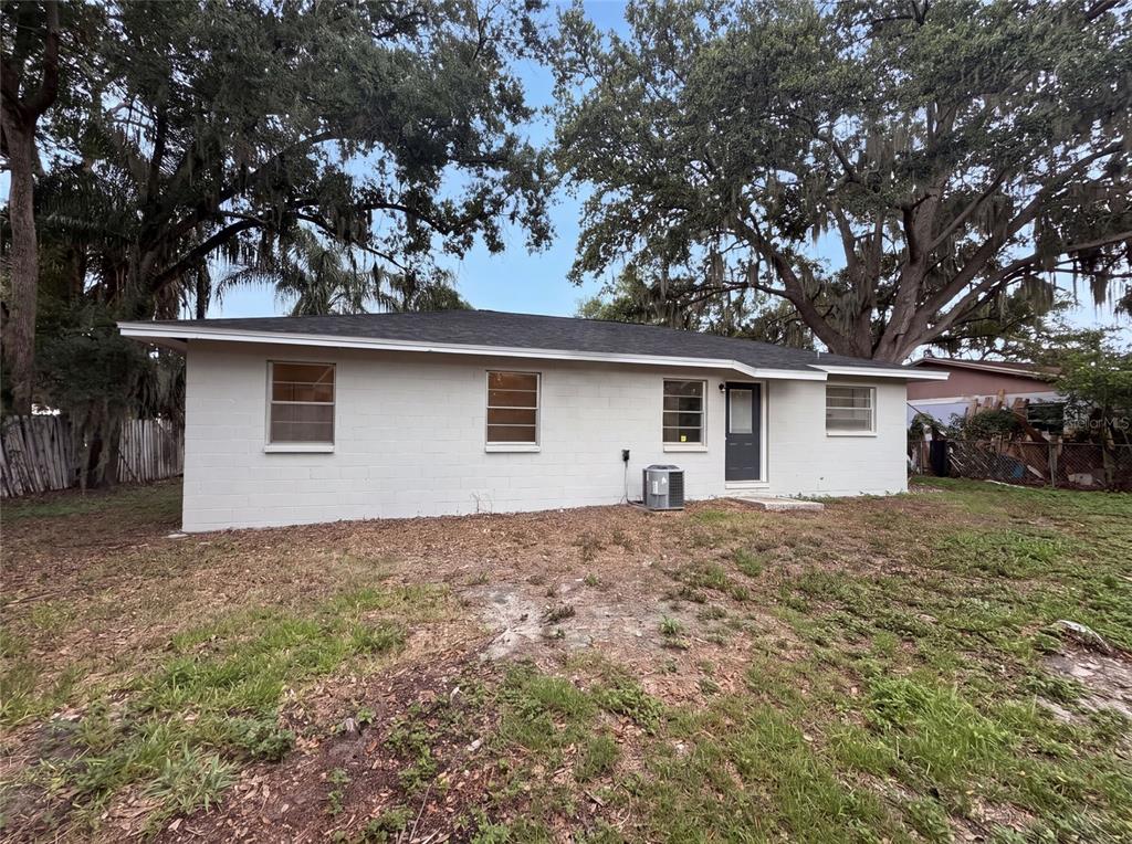 The exterior of a single-story white concrete block house with a dark roof and trees — 4209 E ALENE DRIVE, TAMPA, FL