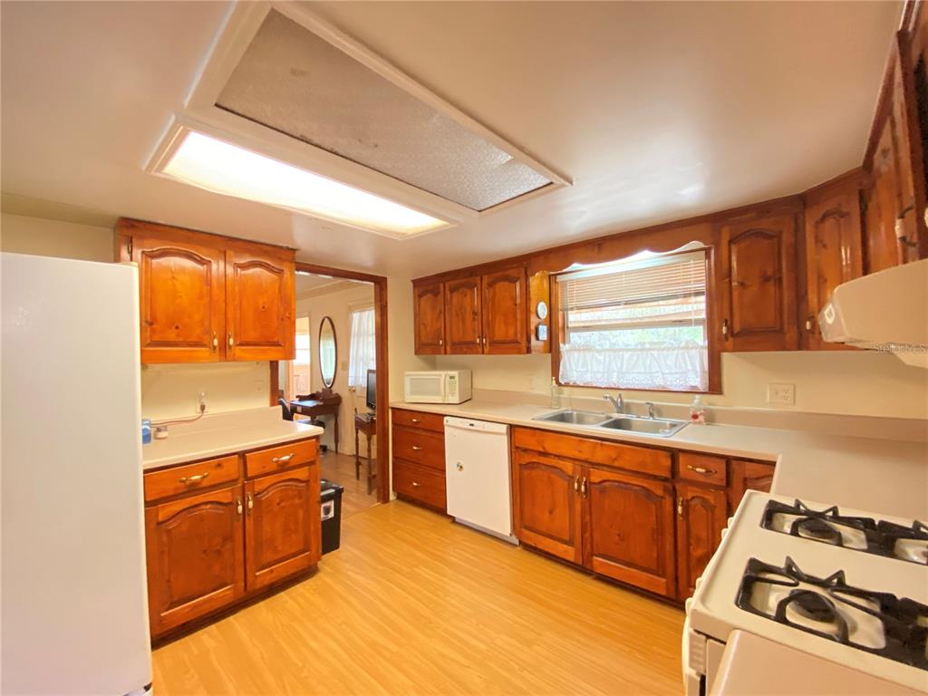 A kitchen with wood cabinets, laminate countertops, a double sink, and light wood-look flooring — 15213 NW 31ST TERRACE, GAINESVILLE, FL