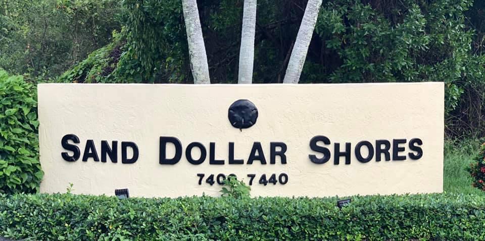 A beige monument sign with black lettering reads Sand Dollar Shores in front of foliage — 7420 S Ocean Drive # 216, Jensen Beach FL 34957, JENSEN BEACH, FL