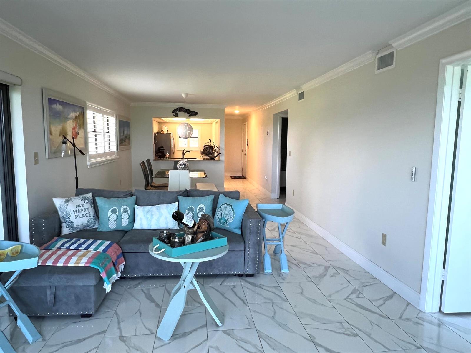 A living room with a grey sectional, light blue accent tables, and white marble-look flooring — 7420 S Ocean Drive # 216, Jensen Beach FL 34957, JENSEN BEACH, FL