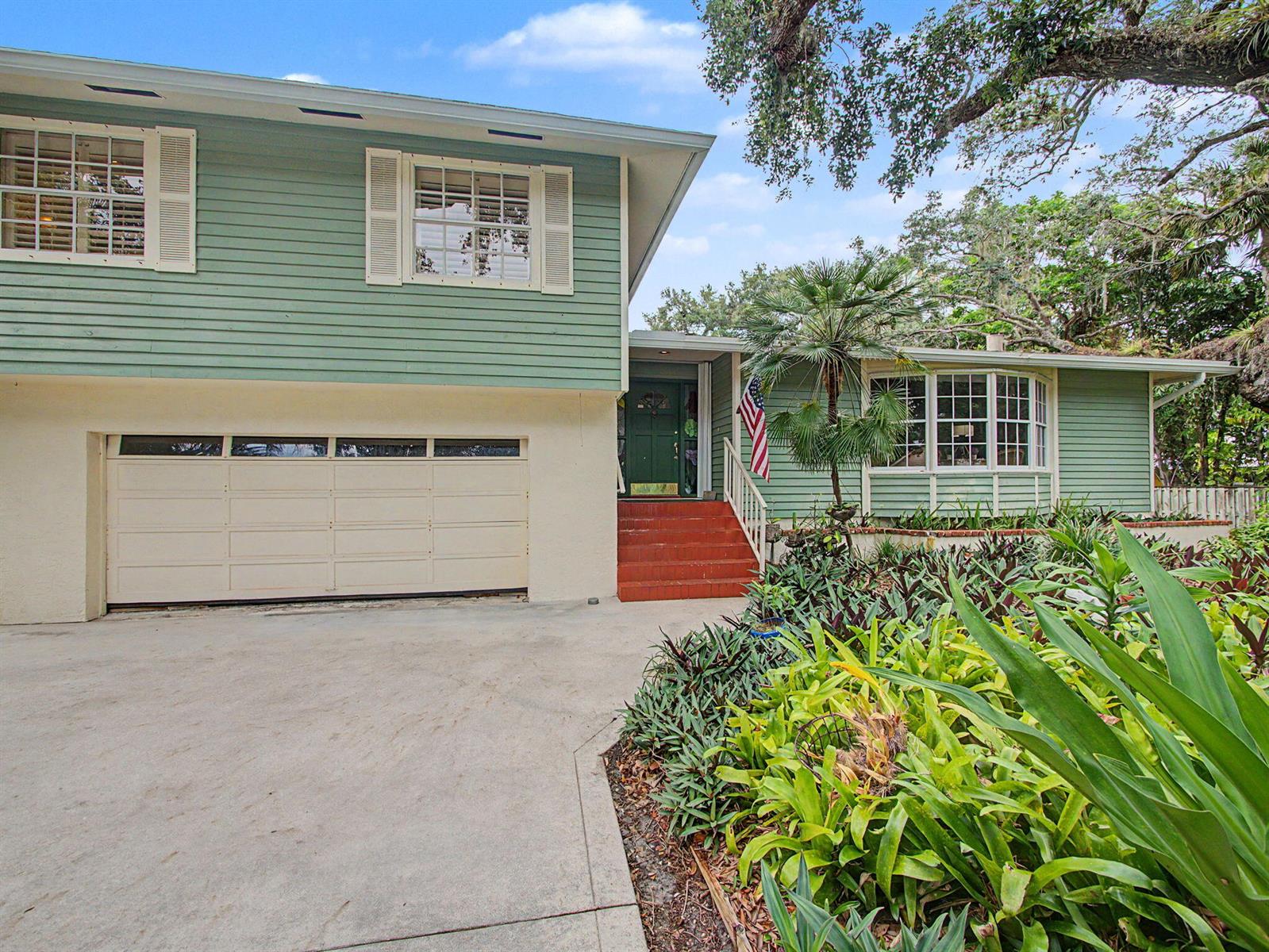 A two-story house with light green siding, a garage, and a front entrance with stairs — 14 Emarita Way, Sewalls Point FL 34996, SEWALLS POINT, FL