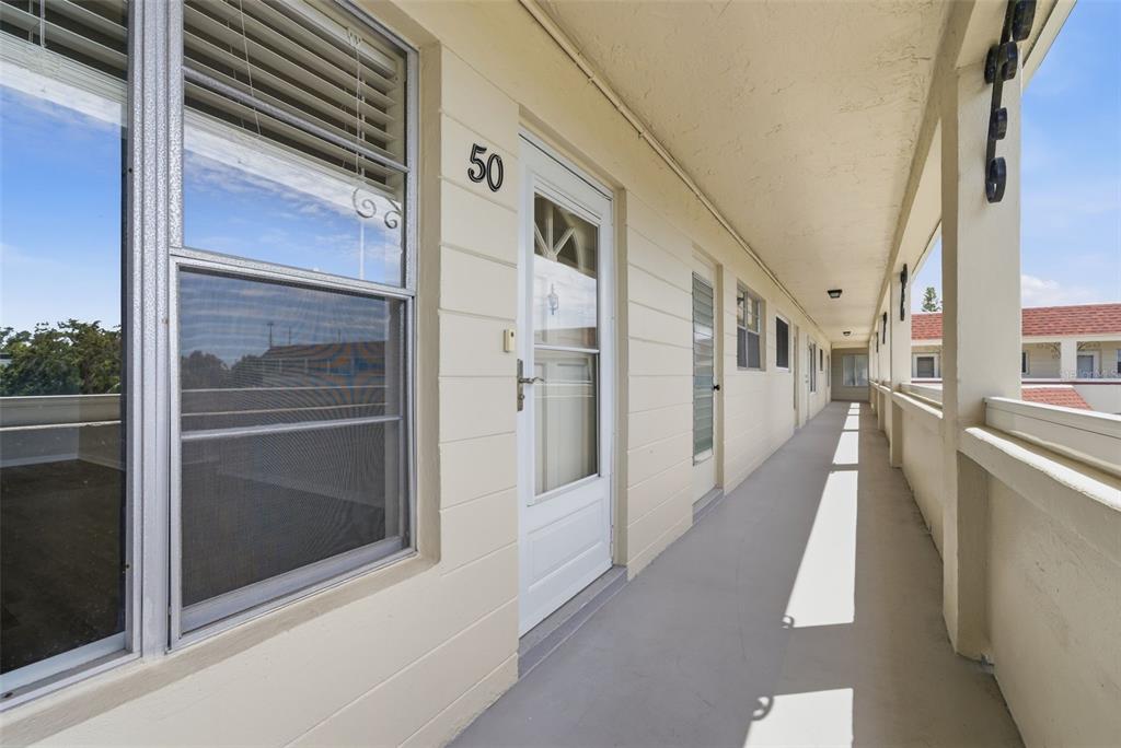 An exterior walkway leads past a white door marked with the number 50 — 2434 AUSTRALIA WAY E UNIT 50, CLEARWATER, FL