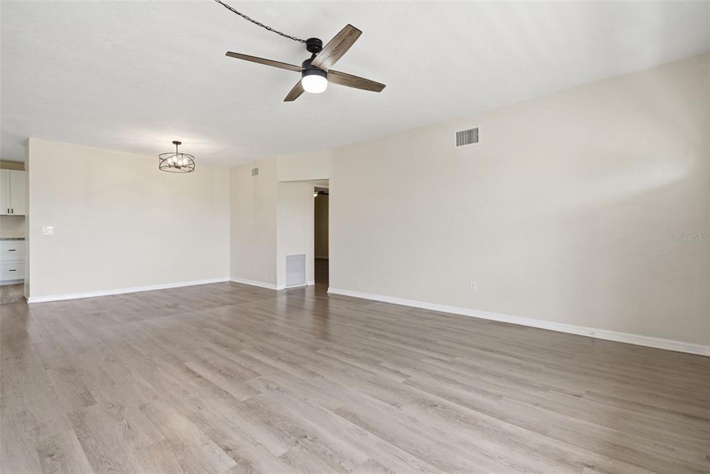 A spacious living room features light wood-look flooring, a ceiling fan, and neutral wall paint — 2434 AUSTRALIA WAY E UNIT 50, CLEARWATER, FL