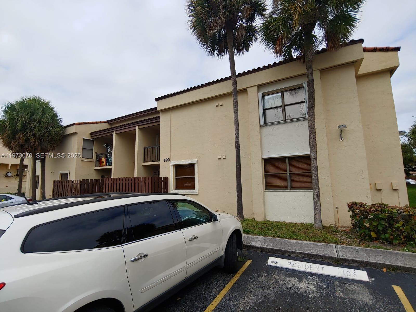 A two-story beige apartment building exterior with palm trees and a parked white car — 690 W Park Dr # 204, Miami FL 33172, MIAMI, FL