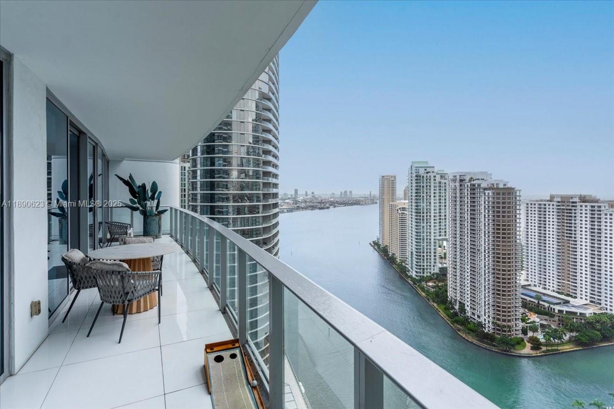 A high-rise balcony features a dining set, a putting green, and views of a waterway — 200 Biscayne Boulevard Way # 3608, Miami FL 33131, MIAMI, FL