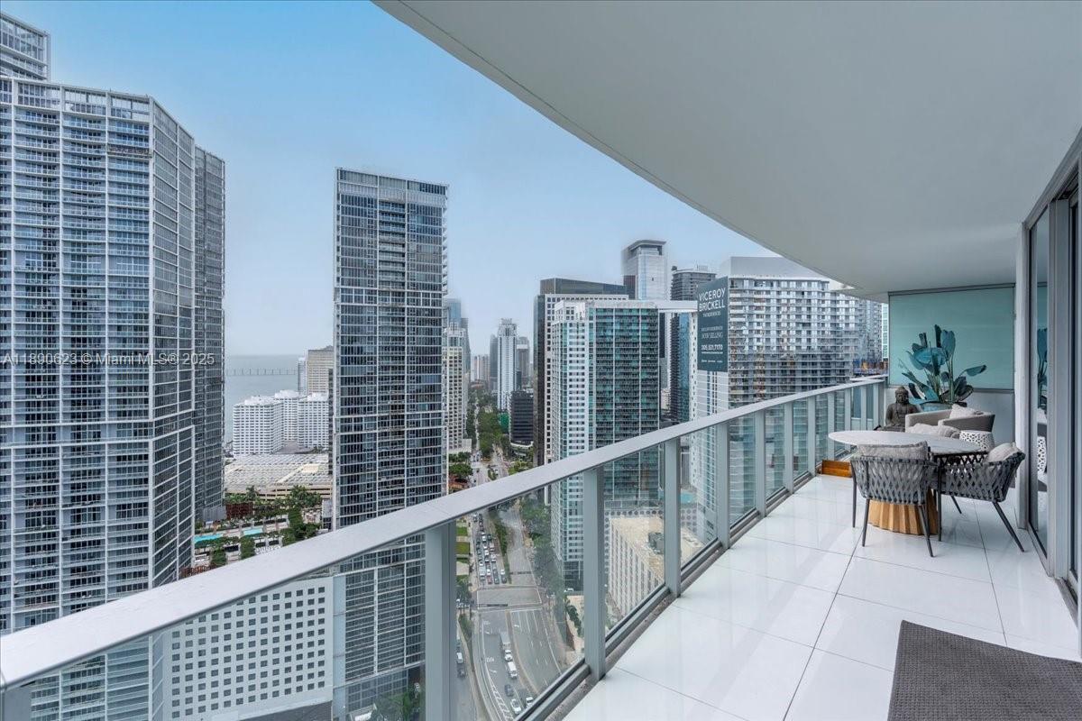 A high-rise balcony with white tile flooring overlooks a dense urban skyline and street — 200 Biscayne Boulevard Way # 3608, Miami FL 33131, MIAMI, FL
