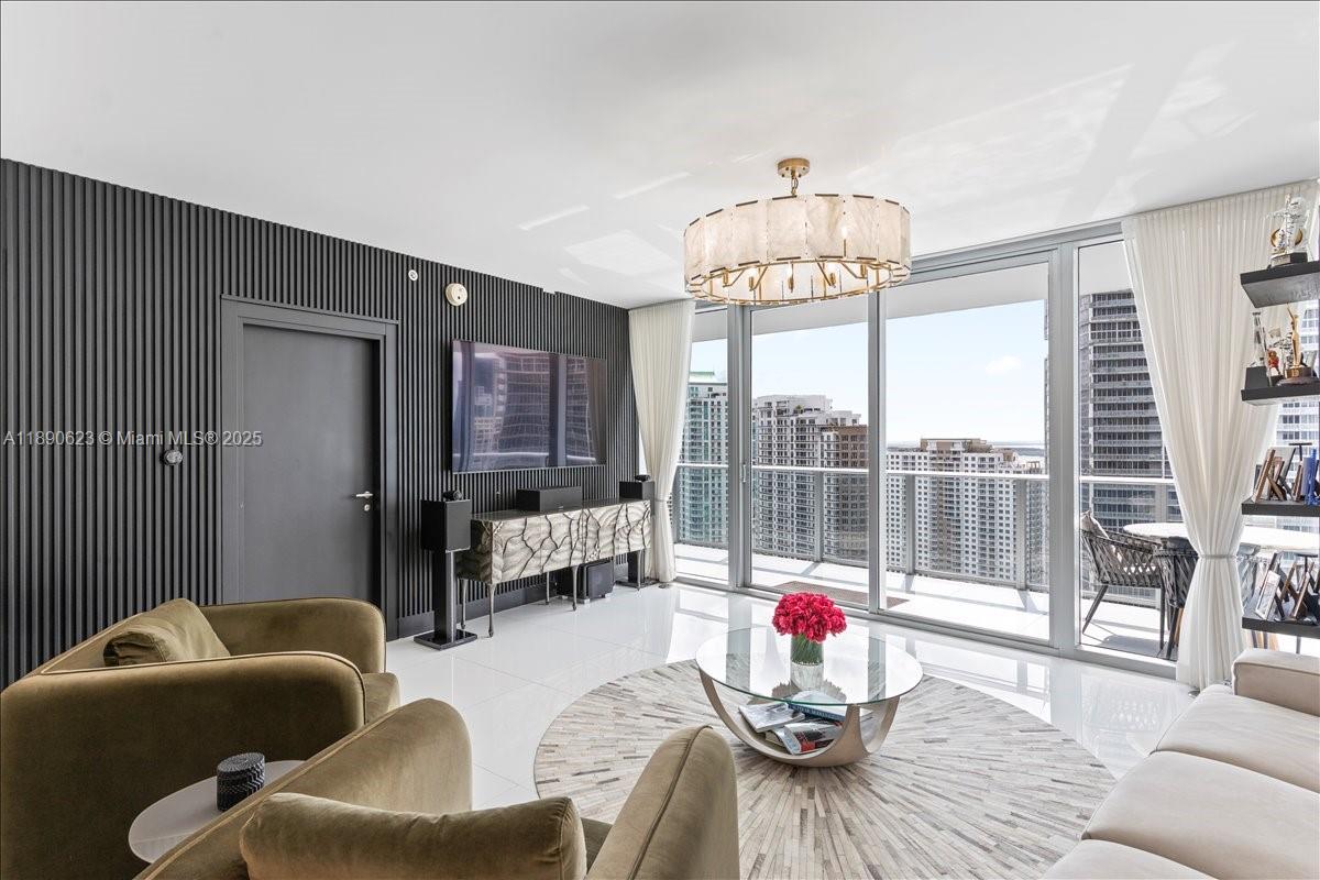 A modern living room features a slatted black wall, white tile floors, and floor-to-ceiling windows — 200 Biscayne Boulevard Way # 3608, Miami FL 33131, MIAMI, FL