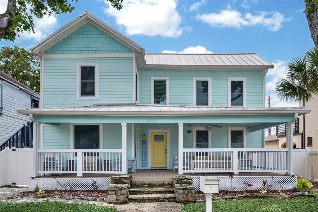 A two-story light blue house with a covered front porch and a yellow front door — 204 PALMETTO STREET, NEW SMYRNA BEACH, FL