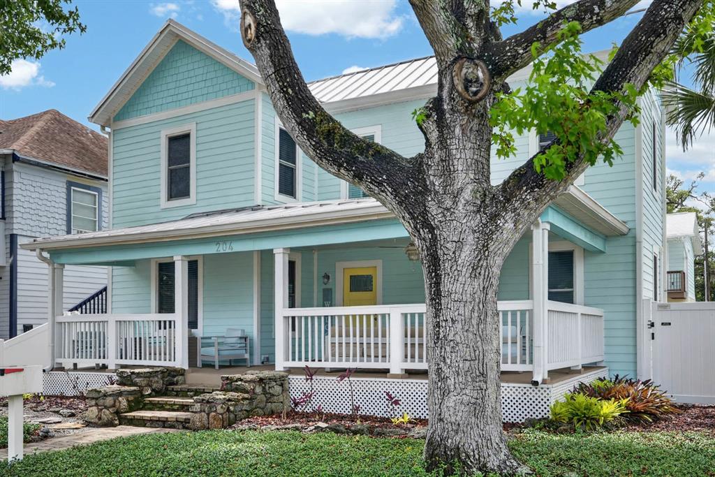 A light blue two-story house features a front porch, white railings, and a yellow door — 204 PALMETTO STREET, NEW SMYRNA BEACH, FL