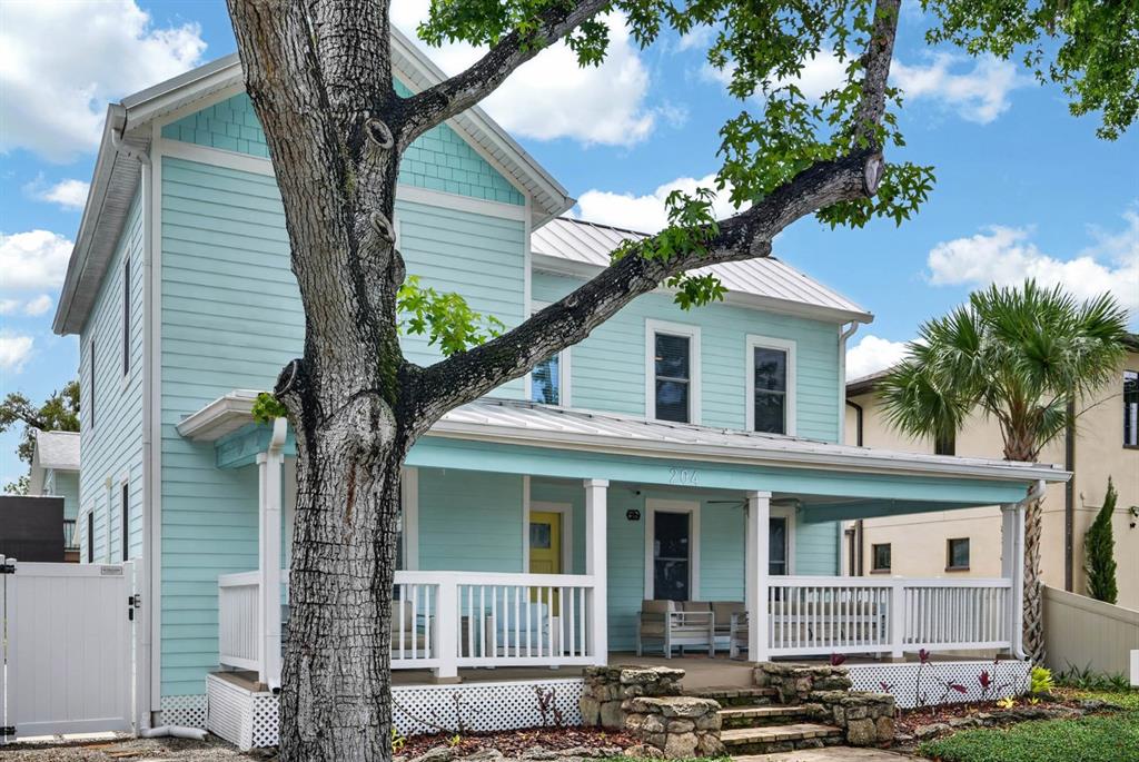 A two-story light blue house features a wrap-around porch and a large tree in front — 204 PALMETTO STREET, NEW SMYRNA BEACH, FL