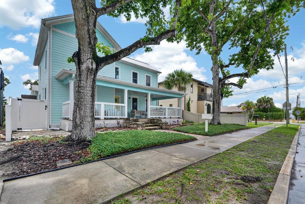A light blue two-story house with a front porch sits behind a sidewalk and trees — 204 PALMETTO STREET, NEW SMYRNA BEACH, FL