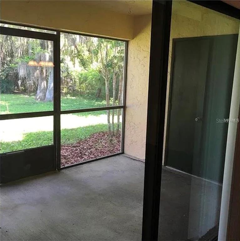 A screened-in porch with a concrete floor overlooks a wooded backyard through large windows — 4358 S LAKE ORLANDO PARKWAY UNIT 3-3, ORLANDO, FL