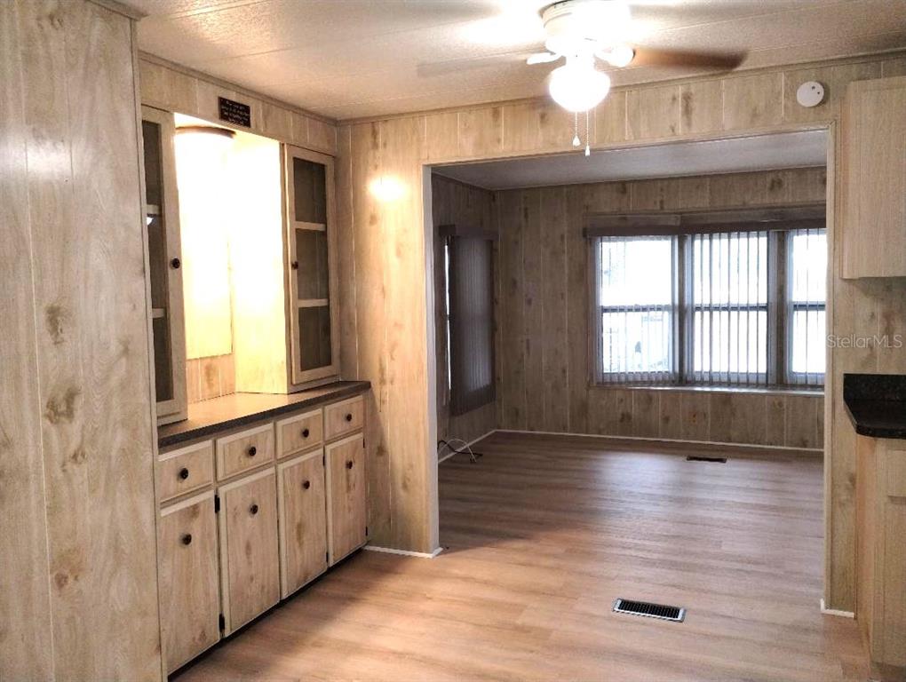 A room with wood-paneled walls, light wood-look flooring, built-in cabinetry, and a ceiling fan — 9283 DENMARSH DRIVE, BROOKSVILLE, FL