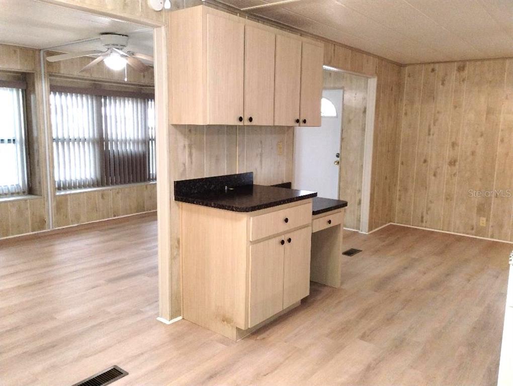 A kitchen area features light wood cabinets, a dark countertop, and wood-paneled walls — 9283 DENMARSH DRIVE, BROOKSVILLE, FL