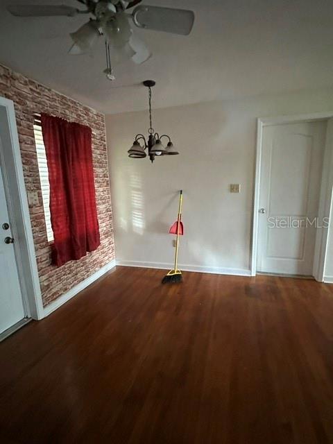An empty room features hardwood floors, a brick-patterned accent wall, and a ceiling fan — 248 S CLAYTON STREET, MOUNT DORA, FL