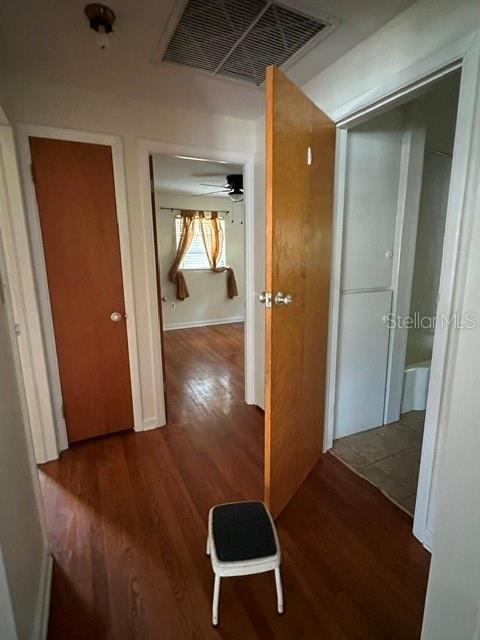 A hallway with wood flooring leads to a bedroom, with a bathroom door on the right — 248 S CLAYTON STREET, MOUNT DORA, FL