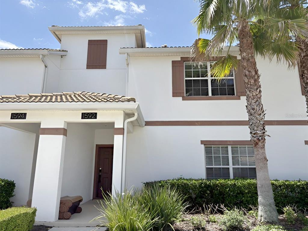 A two-story white stucco townhouse features brown shutters, a tiled roof, and a palm tree — 1592 MOON VALLEY DRIVE, DAVENPORT, FL