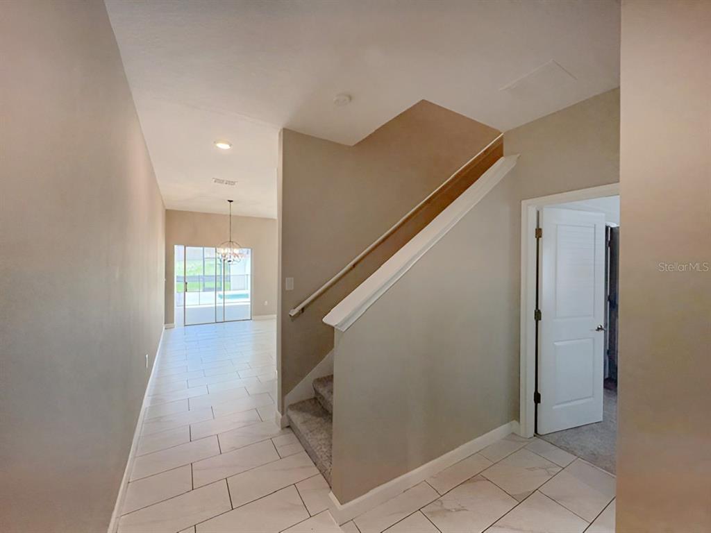 A tiled entryway leads to a carpeted staircase and a doorway into another room — 1592 MOON VALLEY DRIVE, DAVENPORT, FL