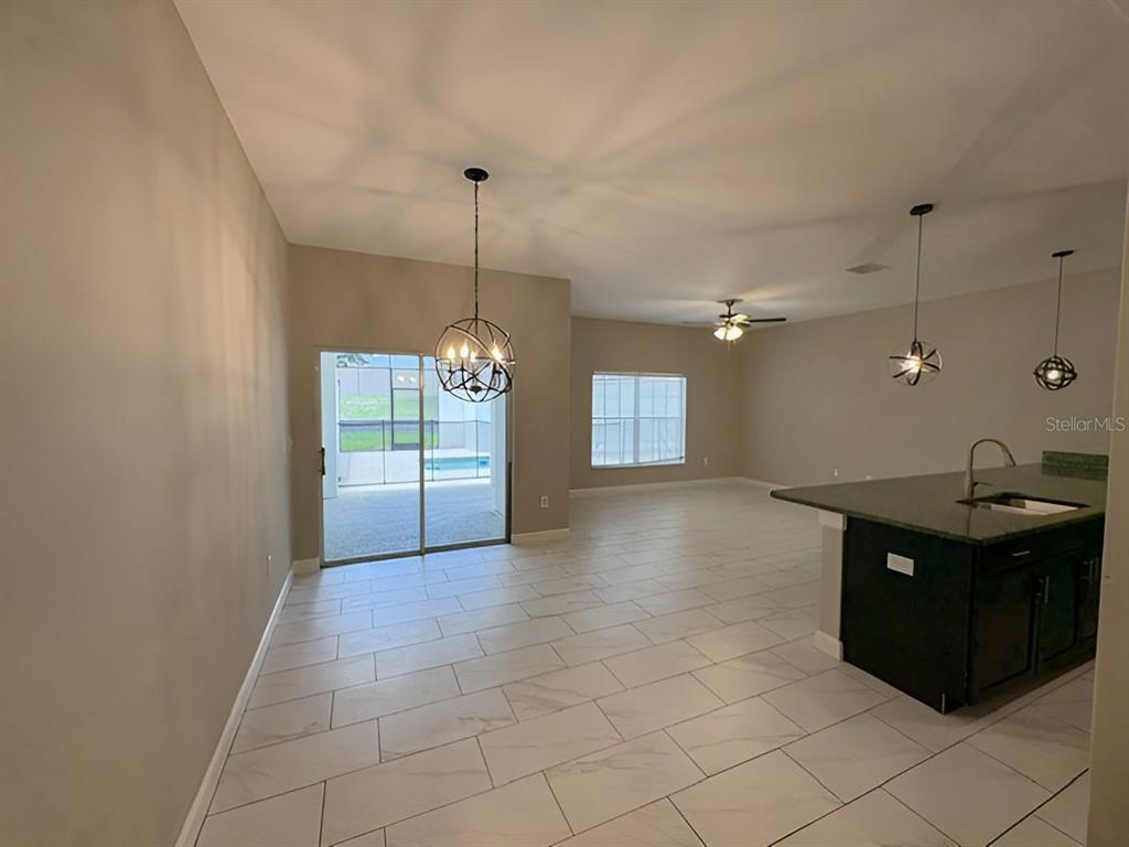 An open-concept dining and kitchen area features tile flooring, pendant lighting, and sliding glass doors — 1592 MOON VALLEY DRIVE, DAVENPORT, FL