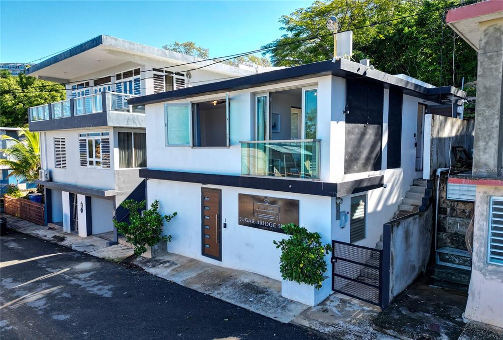 A two-story white building with a balcony, a front door, and a metal sign — 2 BO. BORINQUEN, AGUADILLA, PR