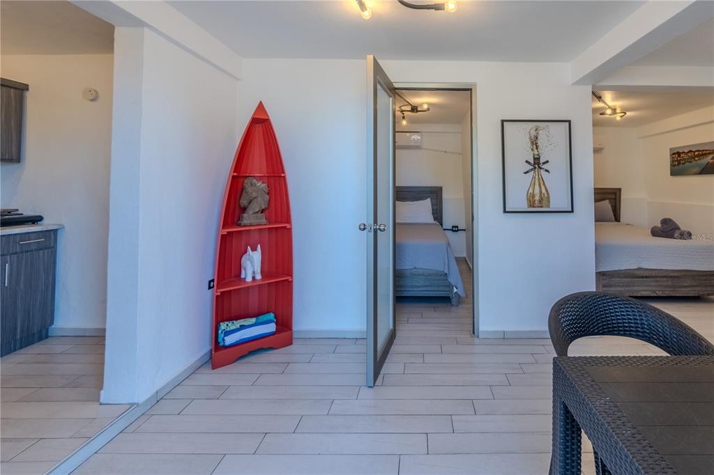 A room with light tile floors, a red boat-shaped shelf, and an open doorway to a bedroom — 2 BO. BORINQUEN, AGUADILLA, PR