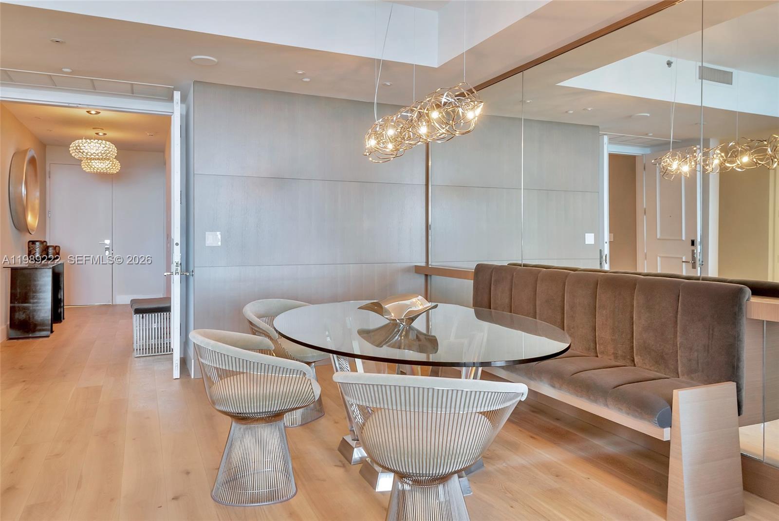 A dining room features a glass-topped table, wire chairs, and a velvet bench against mirrors — 100 S Pointe Dr # 708, Miami Beach FL 33139, MIAMI BEACH, FL