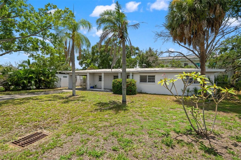 A single-story white brick house features a carport, palm trees, and a grassy front yard — 4635 W BAY VILLA AVENUE, TAMPA, FL