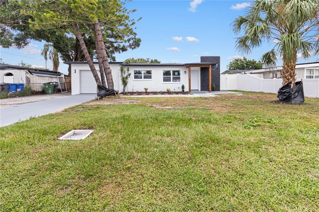 A single-story white house with a black brick accent wall and a front-facing garage — 2917 W CLIFTON STREET, TAMPA, FL