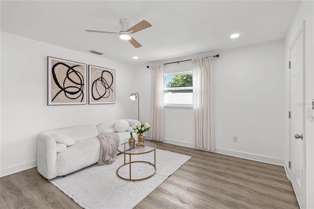A living room features a white sofa, a round glass coffee table, and wood-look flooring — 2917 W CLIFTON STREET, TAMPA, FL