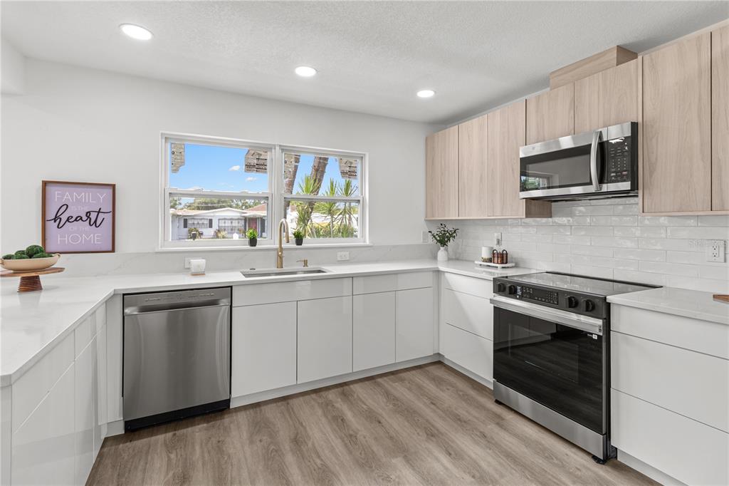 A modern kitchen features white lower cabinets, light wood upper cabinets, and stainless steel appliances — 2917 W CLIFTON STREET, TAMPA, FL