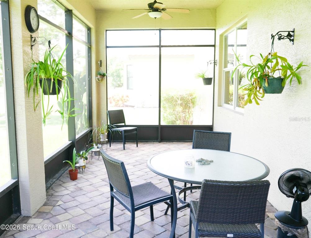 A screened-in patio features a round table, chairs, hanging plants, and a ceiling fan — 5566 57TH WAY, VERO BEACH, FL