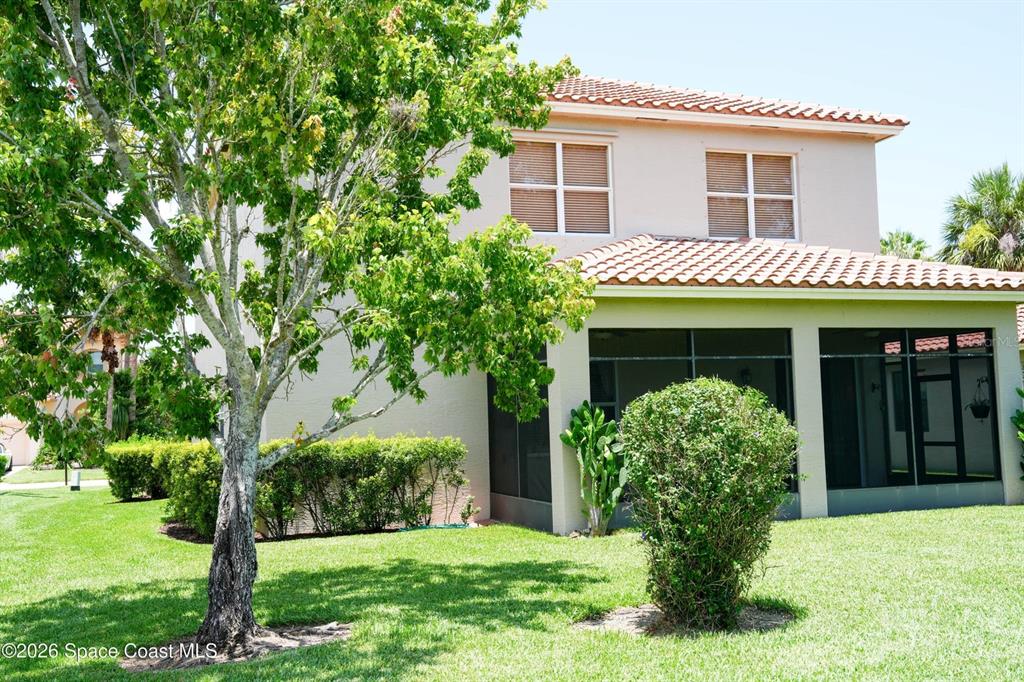 A two-story house with a screened-in patio and a large tree in the yard — 5566 57TH WAY, VERO BEACH, FL